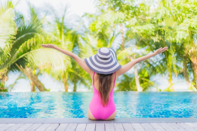 Retrato de uma bela jovem asiática sorrindo relaxando ao redor da piscina em um hotel resort em uma viagem de férias de férias