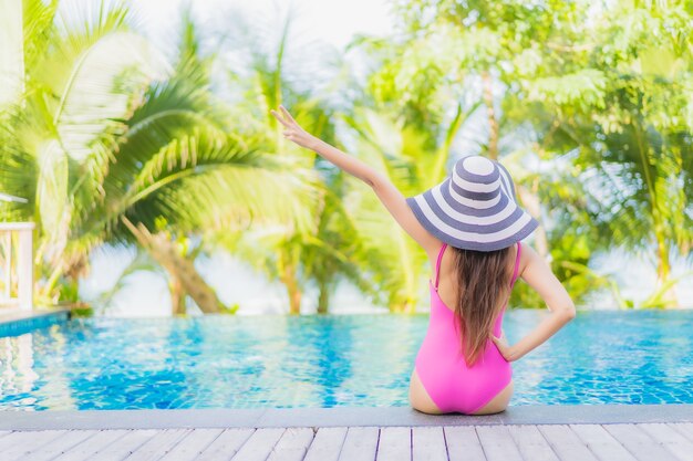 Retrato de uma bela jovem asiática sorrindo relaxando ao redor da piscina em um hotel resort em uma viagem de férias de férias