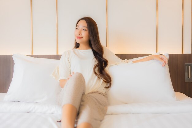 Retrato de uma bela jovem asiática sorrindo relaxar na cama no interior do quarto