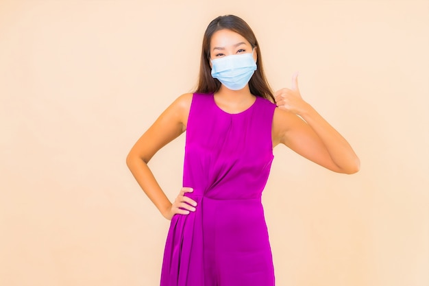 Retrato de uma bela jovem asiática usa máscara para se proteger do vírus covid19 ou corona na cor de fundo