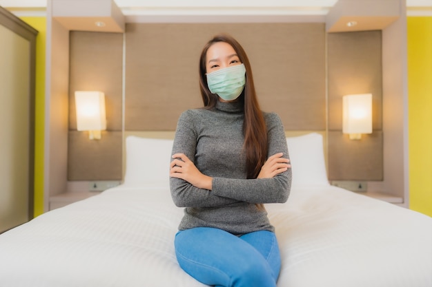 Retrato de uma bela jovem asiática usando máscara no quarto