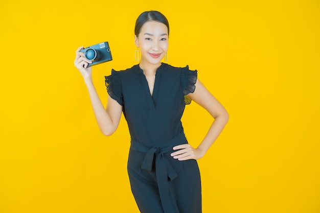 Retrato de uma bela jovem asiática usar a câmera em amarelo