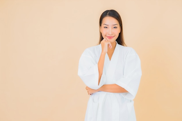 Retrato de uma bela jovem asiática vestindo um roupão de banho com um sorriso em bege