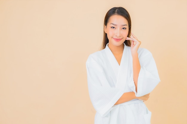 Retrato de uma bela jovem asiática vestindo um roupão de banho com um sorriso em bege