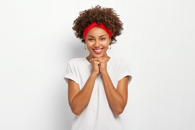 Retrato de uma bela jovem de mãos dadas sob o queixo, sorrindo feliz, vestida com roupa casual, tendo um bom dia com a família