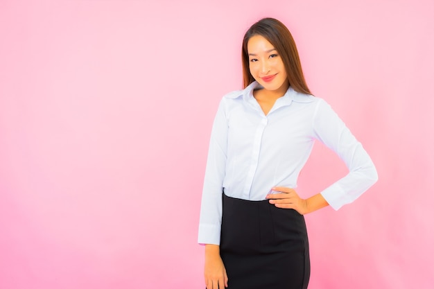 Foto grátis retrato de uma bela jovem mulher asiática de negócios com parede rosa de ação isolada