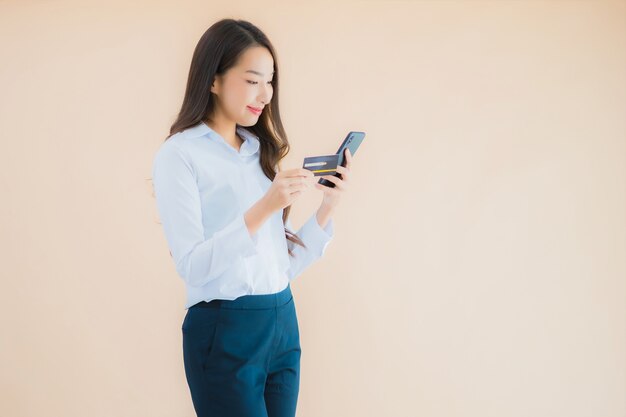 Retrato de uma bela jovem mulher asiática de negócios com telefone e cartão de crédito