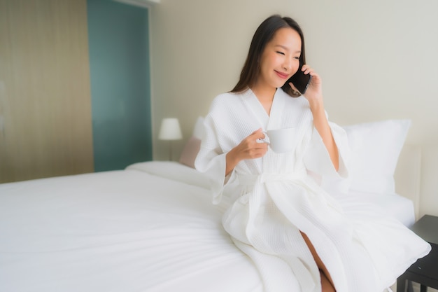 Retrato de uma bela jovem mulher asiática tomando café e falando ao telefone
