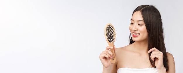 Retrato de uma bela jovem penteando o cabelo maravilhoso isolado na beleza asiática de fundo branco