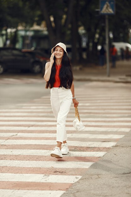 Retrato de uma bela morena. Modelo na cidade de verão. Mulher caminha com o telefone celular.