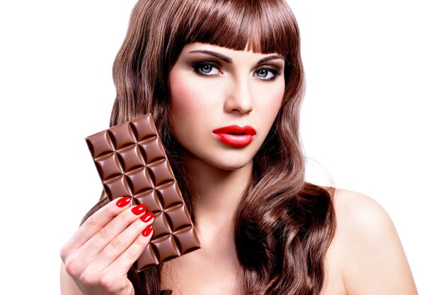 Retrato de uma bela mulher sexy com barra de chocolate. Rosto de closeup com maquiagem brilhante, isolado no branco.