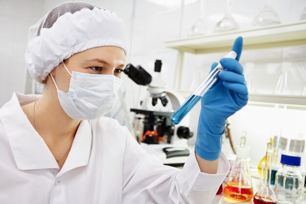 Retrato de uma cientista feminina segurando um tubo cônico com solução líquida