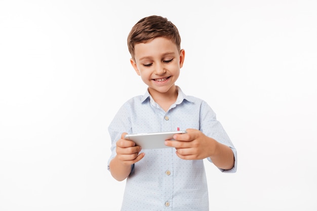 Foto grátis retrato de uma criança bonitinha jogando jogos no smartphone