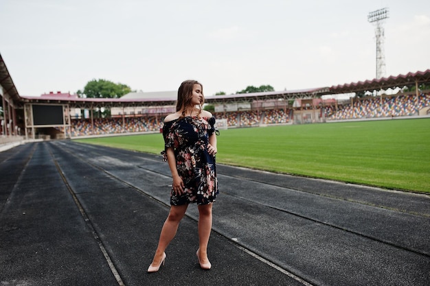 Retrato de uma garota fabulosa de vestido e salto alto na pista do estádio