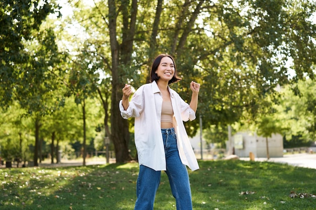 Foto grátis retrato de uma garota feliz dançando e parecendo feliz posando no parque se divertindo andando sozinha