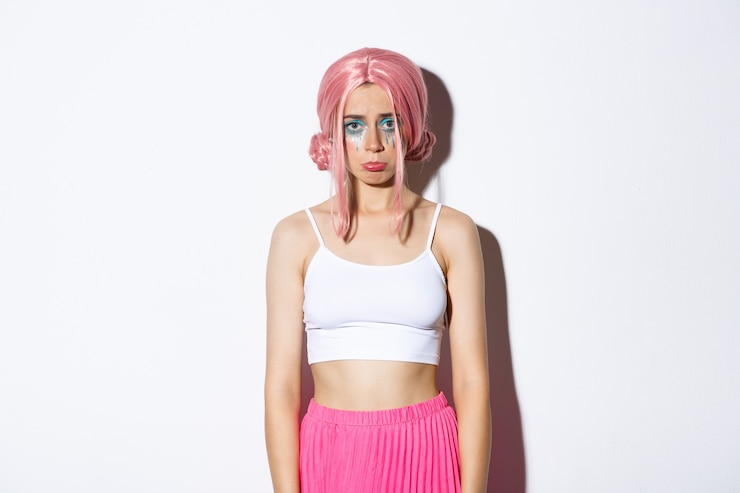Foto grátis retrato de uma garota triste e fofa com maquiagem de halloween e peruca rosa parecendo chateada, emburrada e reclamando de alguma coisa