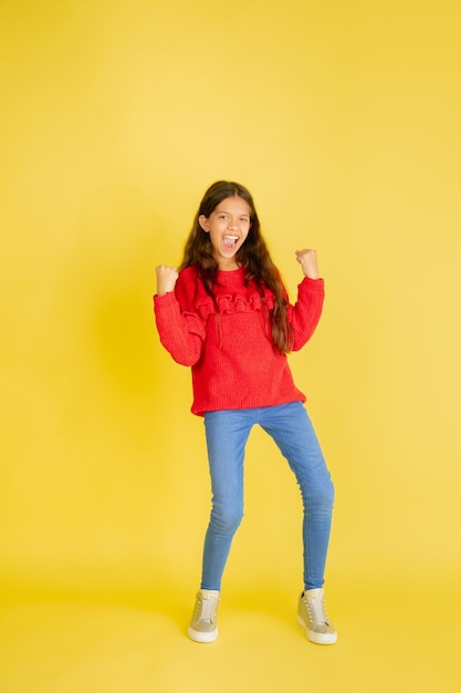 Retrato de uma jovem adolescente caucasiana com emoções brilhantes isoladas em amarelo