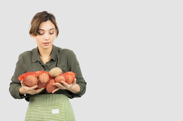 Retrato de uma jovem adorável agricultor segurando batatas no saco. Foto de alta qualidade