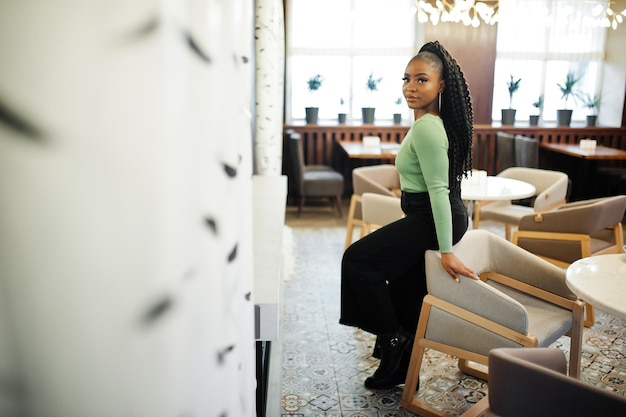 Retrato de uma jovem afro-americana atraente vestindo suéter verde e jeans preto