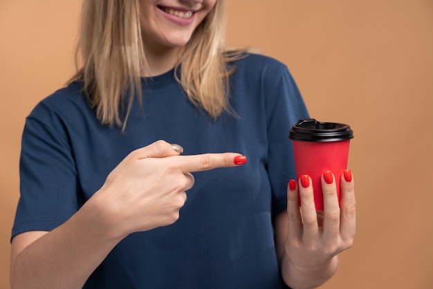 Retrato de uma jovem apontando para uma xícara de café