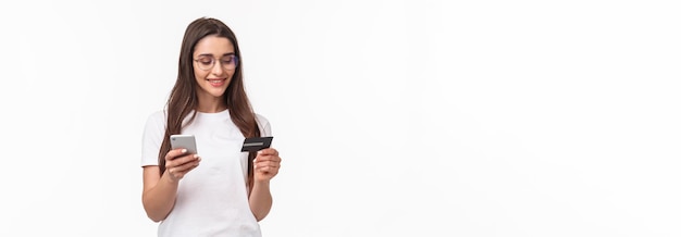 Foto grátis retrato de uma jovem atraente em óculos segurando cartão de crédito e smartphone digite números de dígitos