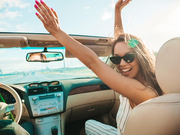 Foto grátis retrato de uma jovem bonita e sorridente hippie em um carro conversível