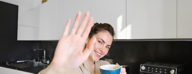 Foto grátis retrato de uma jovem bonita se cobre da câmera rindo e flertando tomando café no