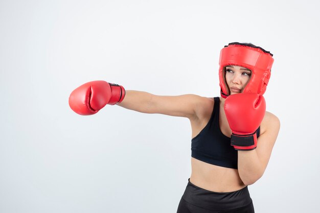 Retrato de uma jovem boxeadora em luvas vermelhas e capacete de combate.