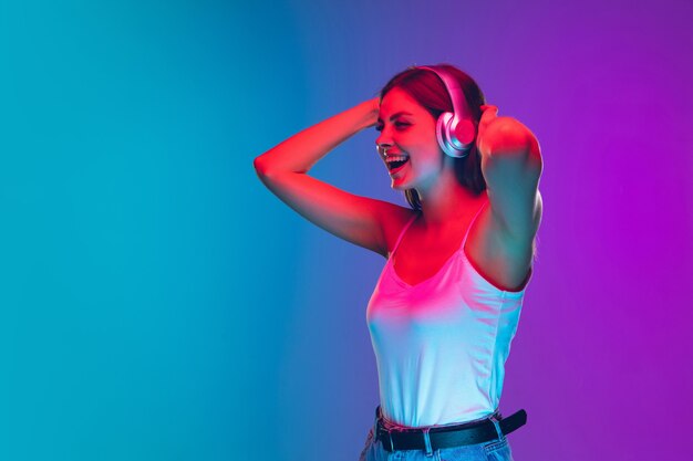 Retrato de uma jovem caucasiana isolado em gradiente roxo-azulado em luz de néon