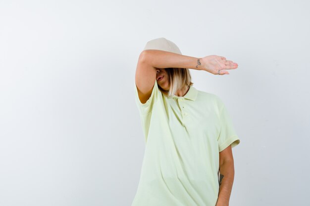 Retrato de uma jovem com a testa apoiada no cotovelo em uma camiseta, boné e vista frontal cansada