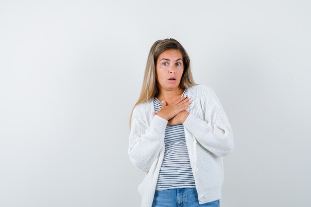Retrato de uma jovem com as mãos no peito em uma camiseta, jaqueta e olhando a vista frontal com medo