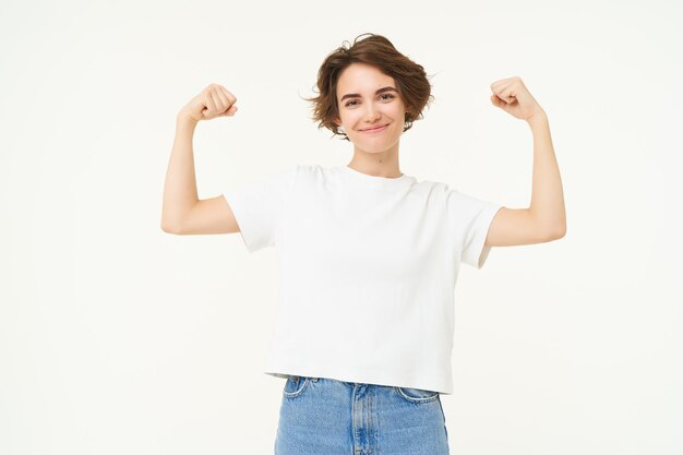 Foto grátis retrato de uma jovem confiante e forte flexionando bíceps mostra seus músculos nos braços com orgulho