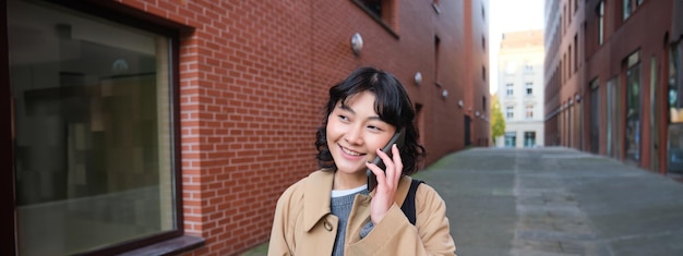 Retrato de uma jovem coreana andando pela rua com telefone conversando com alguém faz uma ligação tem