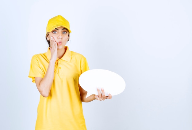 Retrato de uma jovem de uniforme amarelo, segurando um balão de fala em branco vazio.