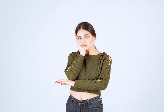 Retrato de uma jovem e bela modelo em pé e posando sobre uma parede branca.