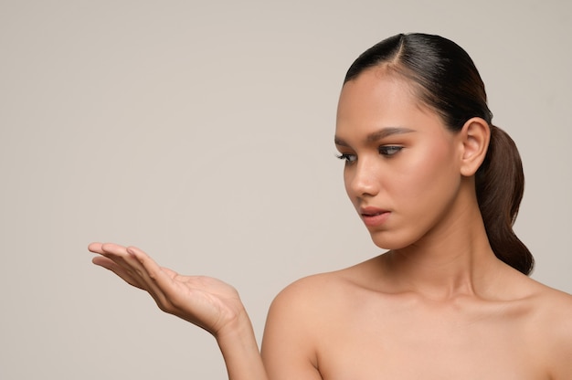 Retrato de uma jovem e bela modelo feminino mostrando a palma da mão vazia