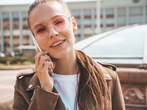 Retrato de uma jovem e bela mulher sorridente, falando no telefone Menina na moda em roupas de verão casual Engraçado e positivo feminino posando na rua