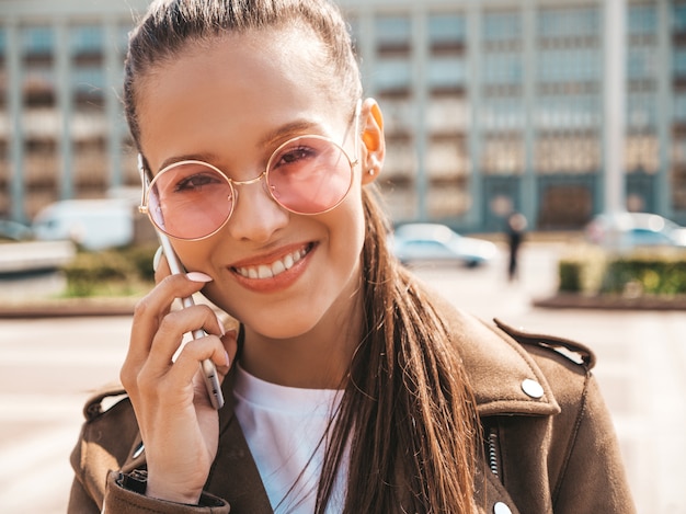 Retrato de uma jovem e bela mulher sorridente, falando no telefone Menina na moda em roupas de verão casual Engraçado e positivo feminino posando na rua