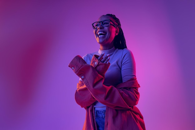 Retrato de uma jovem elegante sorrindo rindo posando isolado sobre fundo roxo rosa gradiente