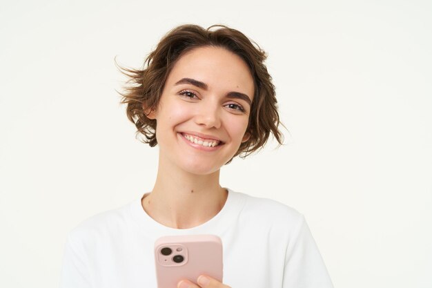 Foto grátis retrato de uma jovem em pé com um celular rosa usando o aplicativo para smartphone fazendo compras on-line