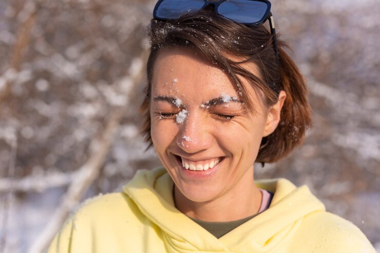 Foto grátis retrato de uma jovem em uma floresta de inverno em um dia ensolarado com um sorriso branco como a neve, brincando