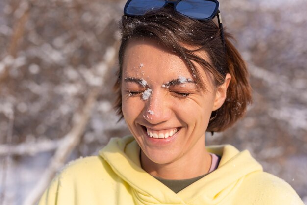 Retrato de uma jovem em uma floresta de inverno em um dia ensolarado com um sorriso branco como a neve, brincando