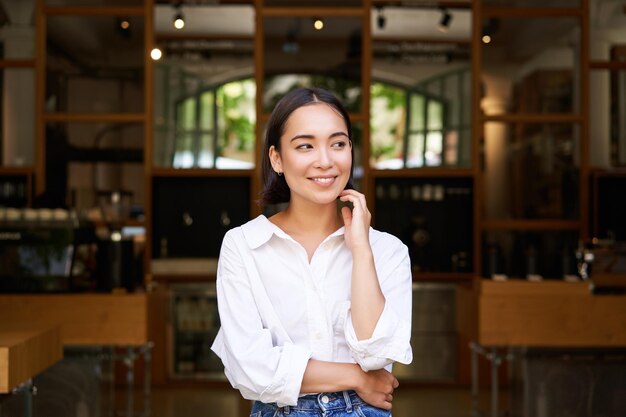 Retrato de uma jovem empresária asiática, empresária ou gerente, sentada confiante, sorrindo para a câmera com os braços cruzados