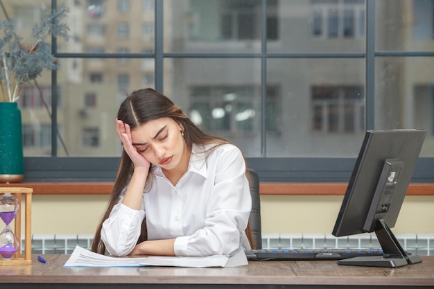 Retrato de uma jovem empresária sentada à mesa e se sentindo cansada