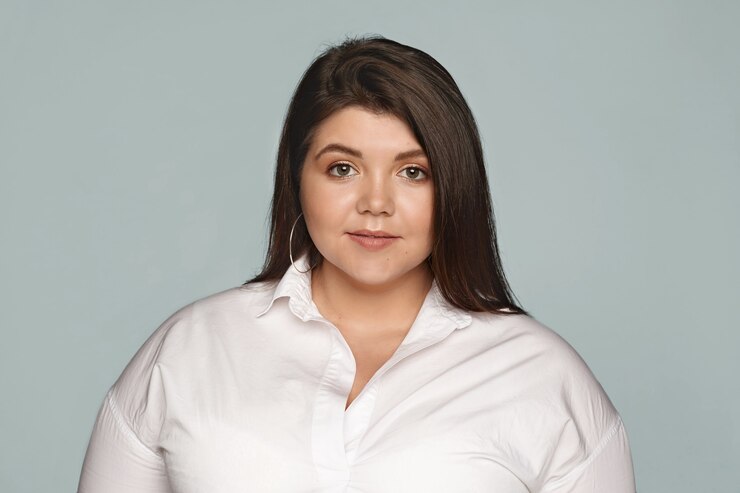 Foto grátis retrato de uma jovem encantadora plus size vestida com roupa formal posando. imagem isolada de uma linda mulher com bochechas rechonchudas e cabelo preto liso e solto, com aparência séria ou calma