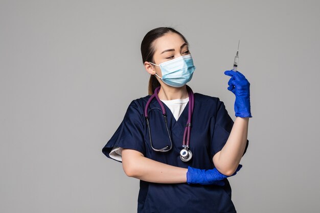 Retrato de uma jovem enfermeira asiática séria em máscara médica, segurando uma seringa com a vacina do vírus