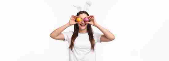 Foto grátis retrato de uma jovem engraçada e despreocupada em orelhas de coelho fazendo olhos de ovos coloridos comemora