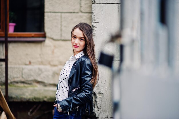 Retrato de uma jovem estilosa vestindo jaqueta de couro e jeans rasgados nas ruas da cidade Estilo de moda de rua