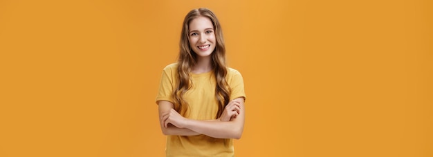 Foto grátis retrato de uma jovem estudante amável e simpática em camiseta casual com comprimento natural ondulado