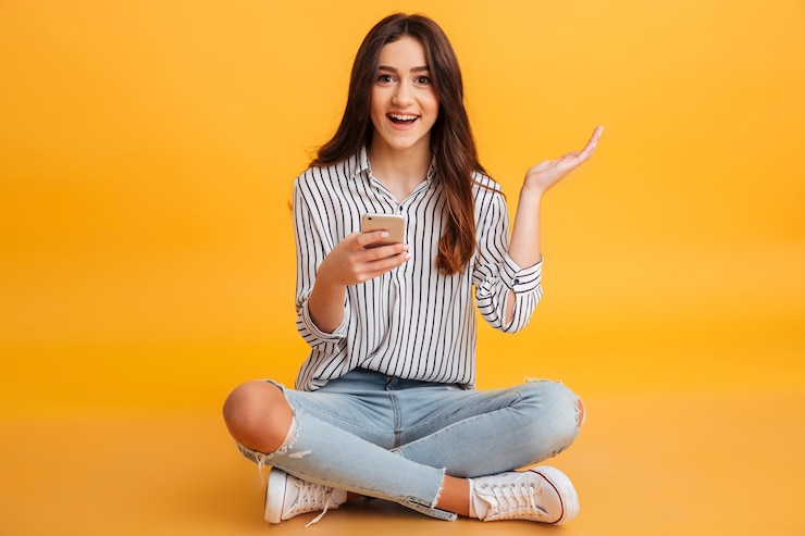 Foto grátis retrato de uma jovem excitada segurando o telefone móvel